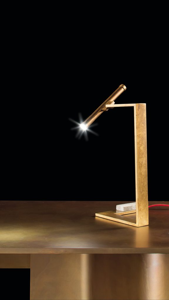 Let Flat Lamps with brass pipe structure, multi directional light, power lead with red silk cover, counterweight in stone on a black background.