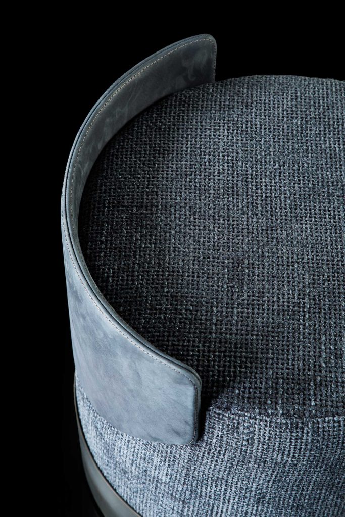 Closeup of Gelly Pouf upholstered in gray leather on a black background.
