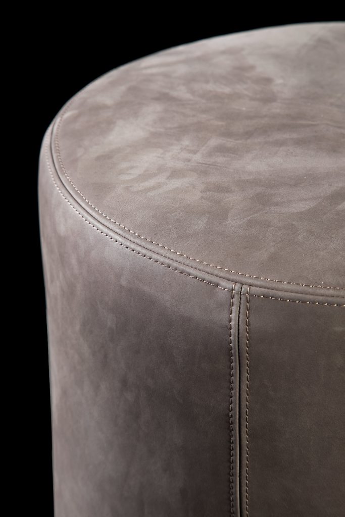 Closeup of Gelly Pouf upholstered in pink leather on a black background.