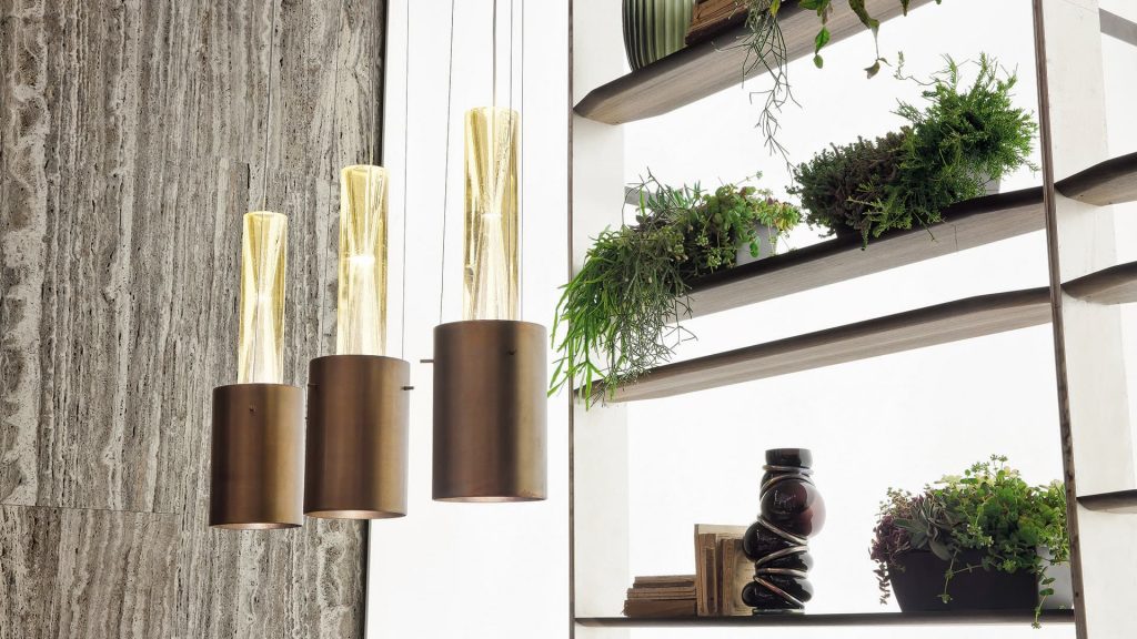 Three pendant Ghost Lights. Central element in resin and brass light diffuser next to a shelf.