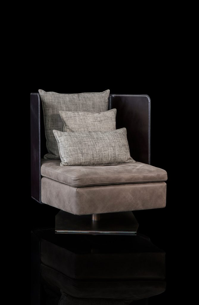 Human Armchair upholstered in brown leather and three gray cushions. Structure armchair with metal base frame and central leg on a black background.