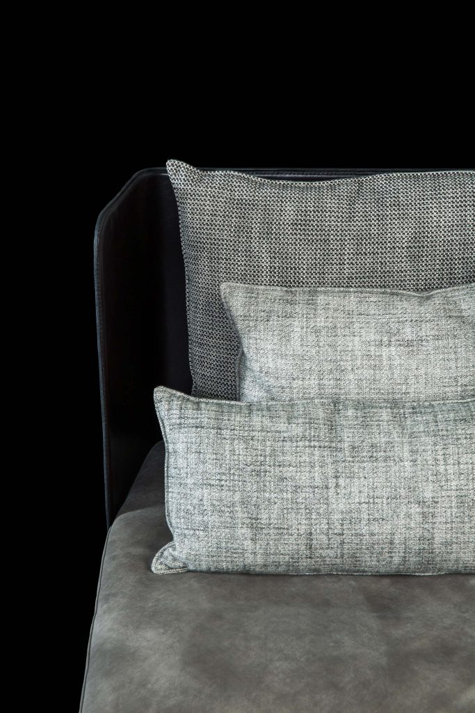 Human Armchair upholstered in brown leather and three gray cushions. Structure armchair with metal base frame and central leg on a black background.