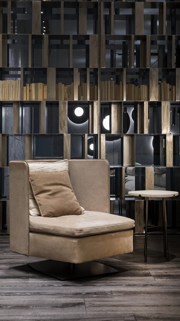 Human Armchair upholstered in brown leather and three gray cushions. Structure armchair with metal base frame and central leg in a living room.
