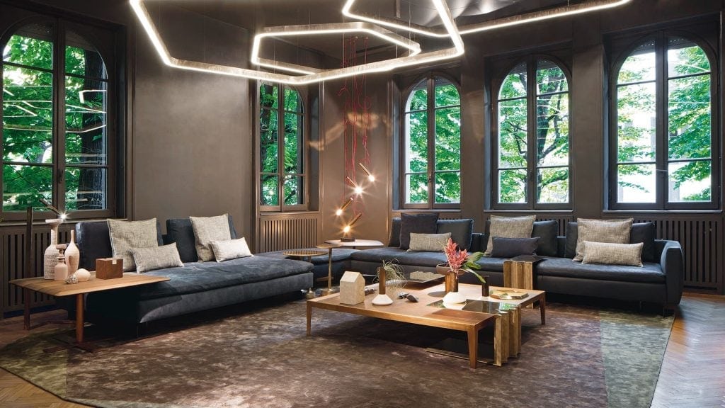 Two Human Sofas with armrest and backrest upholstered in black fabric with black brass legs in a living room.