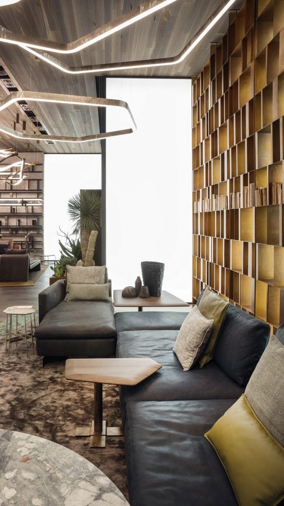 Two Human Sofas with armrest and backrest upholstered in black fabric with black brass legs in a living room.