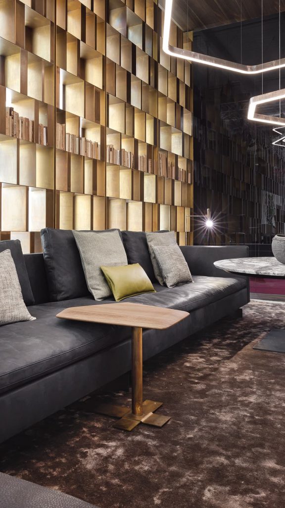 Human Sofa with armrest and backrest upholstered in black fabric with black brass legs in a living room.