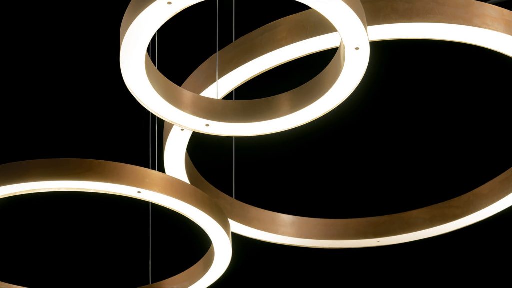 three thick ring-shaped lamps in a golden tone with LED lighting