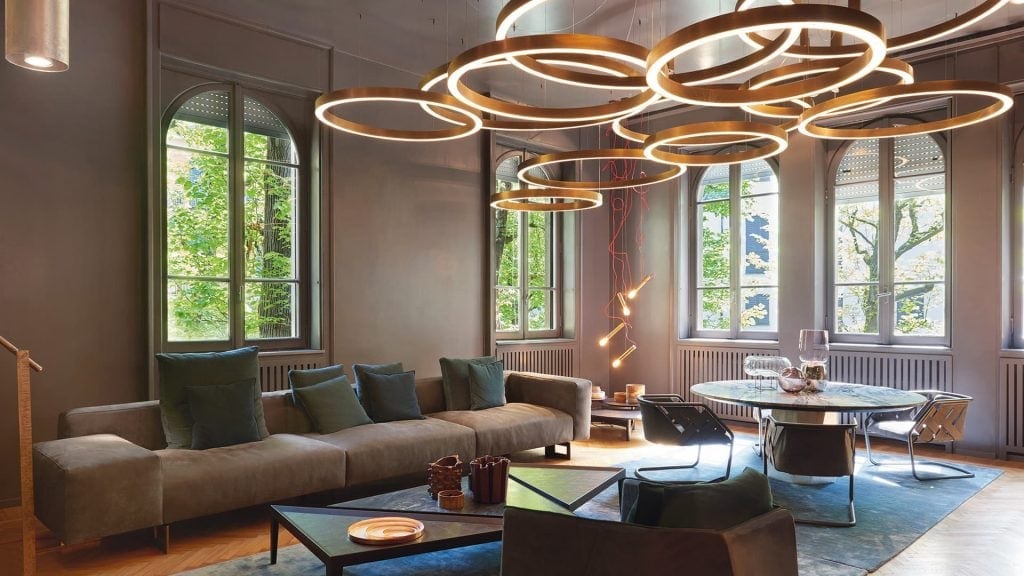 eight lamps made on a steel base in the shape of thick rings in different shapes in a golden tone in a living room