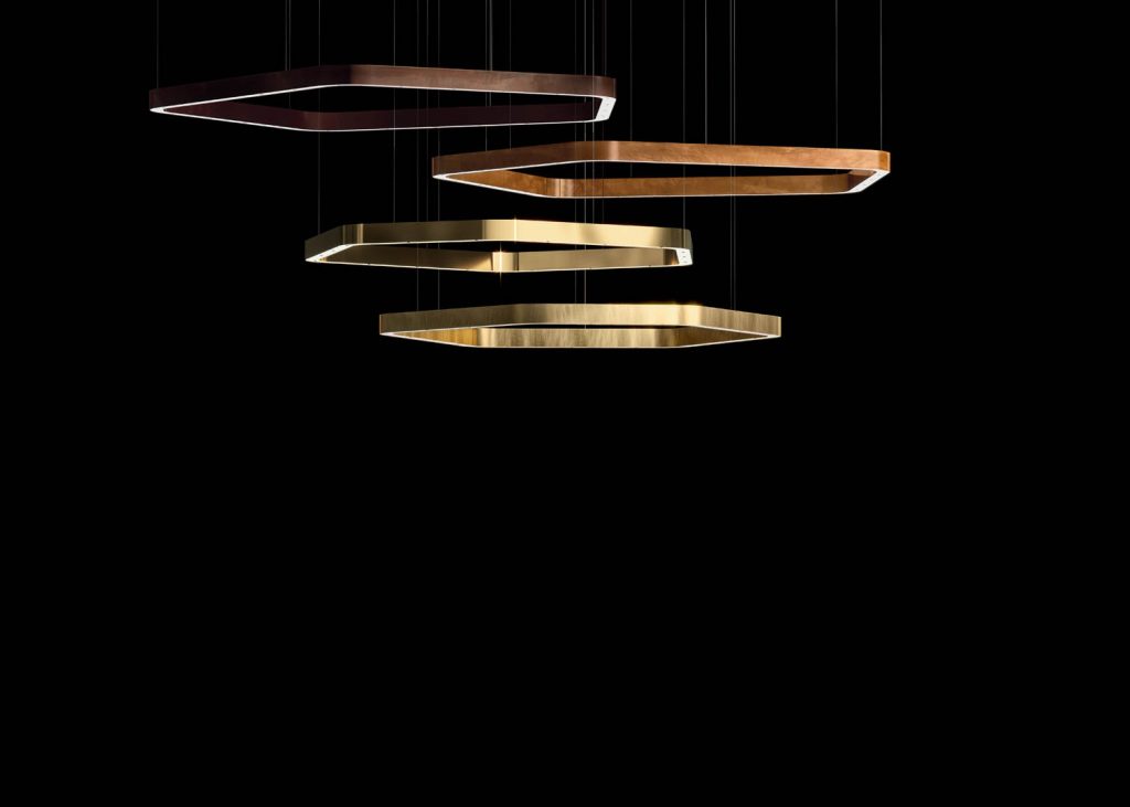 four ceiling lamps made of metal in a golden color tone in the shape of a polygon on a black background.