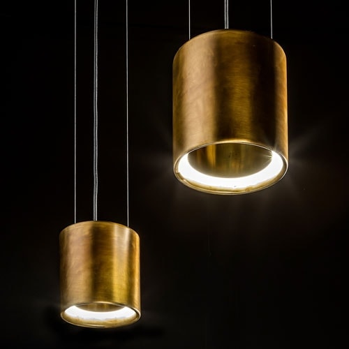two lamps in the shape of long rings on a burnished brass base in a gold tone on a black background