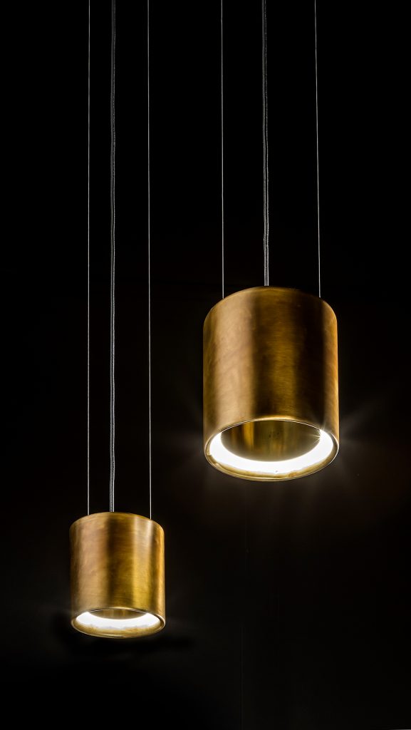 two lamps in the shape of long rings on a burnished brass base in a gold tone on a black background
