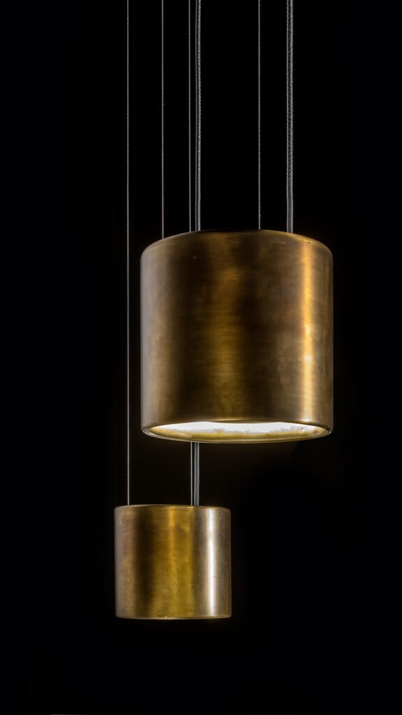 two lamps in the shape of long rings on a burnished brass base in a gold tone on a black background