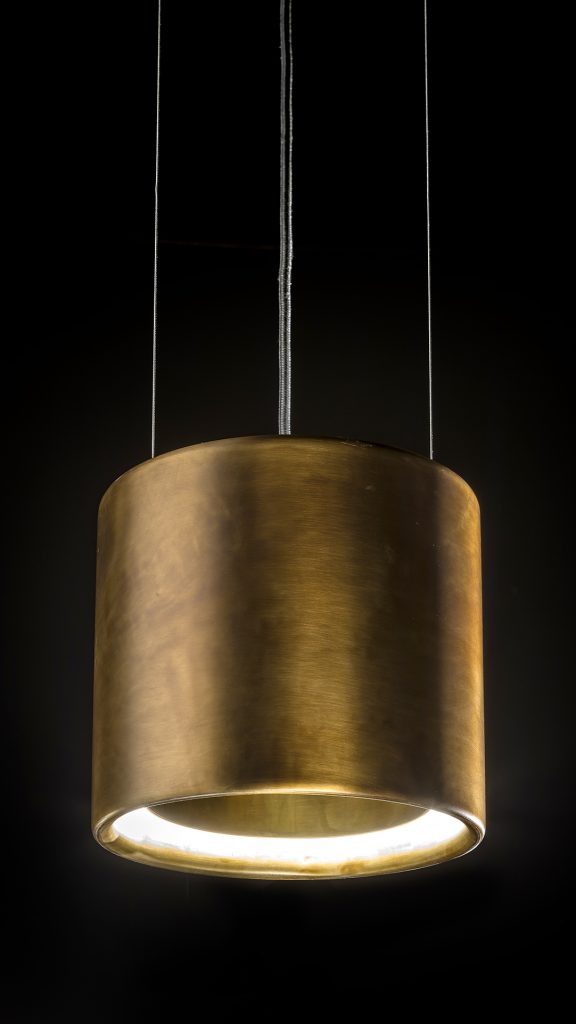 lamp in the shape of long rings on a burnished brass base in a gold tone on a black background
