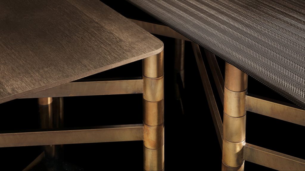 Closeup of Network Table, top in brown wood, frame made of rectangular brass tubes on a black background.