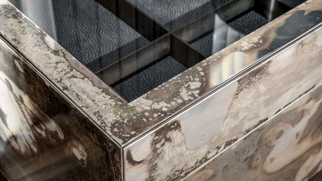 Closeup of Noctis Vanity cabinet with three doors with shelve bronzed tempered glass Outside covered with burnished steel.