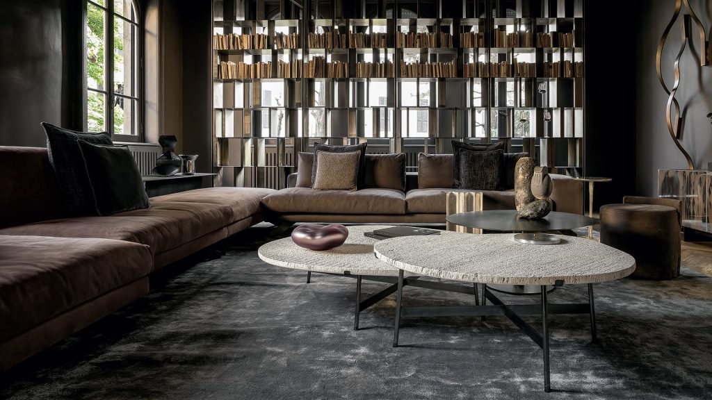 Two Opus Sofas upholstered in gray fabric with four legs in black steel with poufs and a table in a living room.