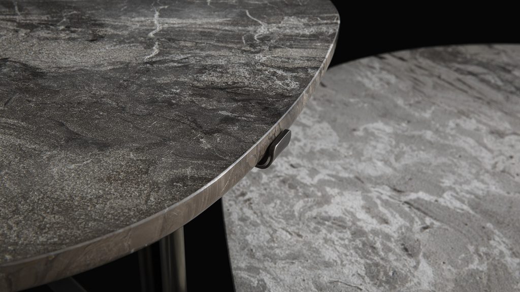Closeup of two round Primitive Tables top in white and gray stone on a black background.