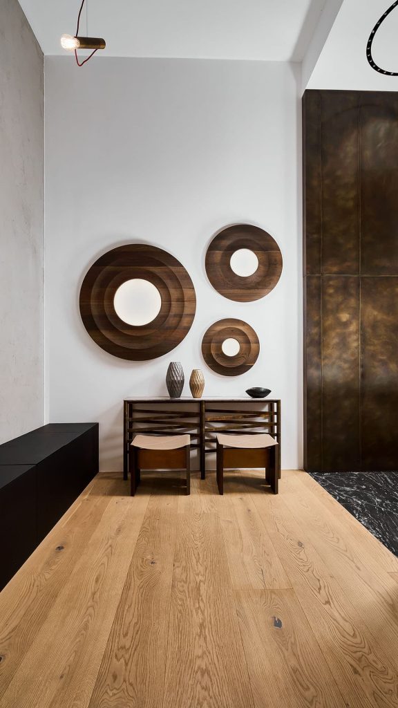 Two Rio Stools, structure and two legs in black wood with central crosspiece covered in black brass; seat in brown leather in a living room.