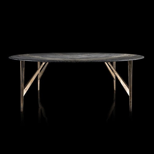 Round Saetta Table, four legs in sandlasting brass and bronze. Top in gray and black stone on a black background.