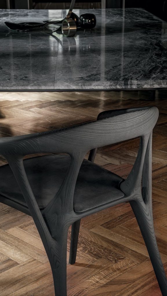 Savanna dining chair in black wood with four legs. Seat covered with black leather on a brown floor.