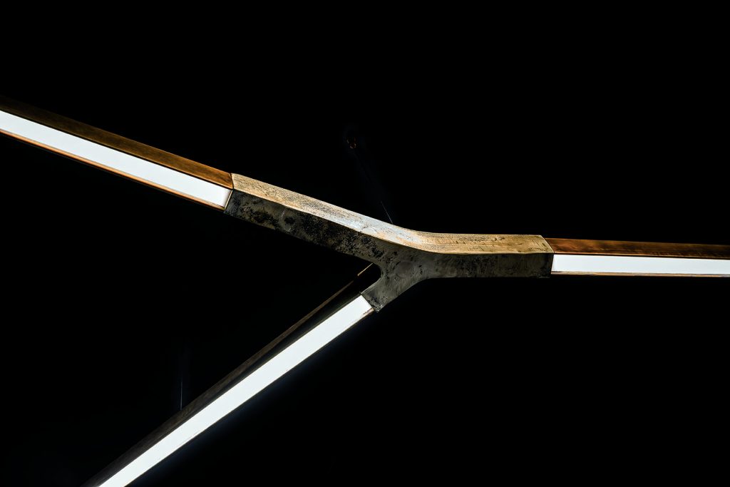 Starlight Horizontal led lamp with with Y shaped central body sandcasting silver using suspension cables on a black background.
