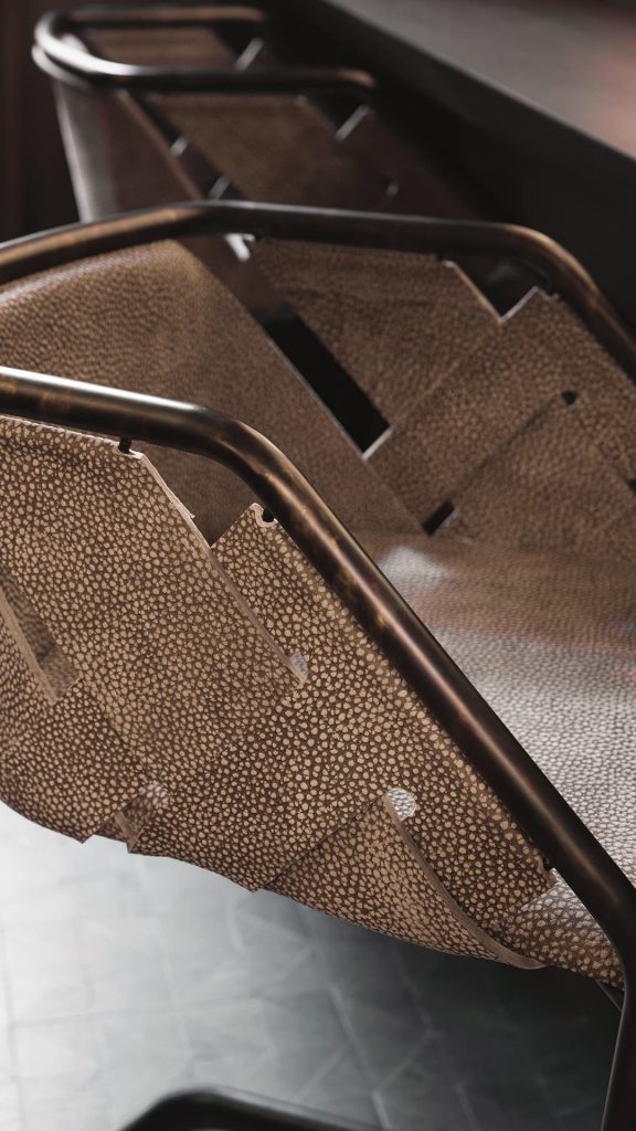 Closeup of Strip Stool. Structure in curved black metal frame, seat covered with brown leather on a grey background.