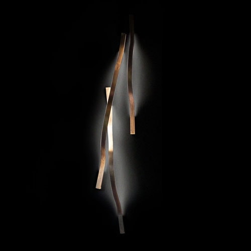wall lamp made of burnished brass with a curved design on a black background