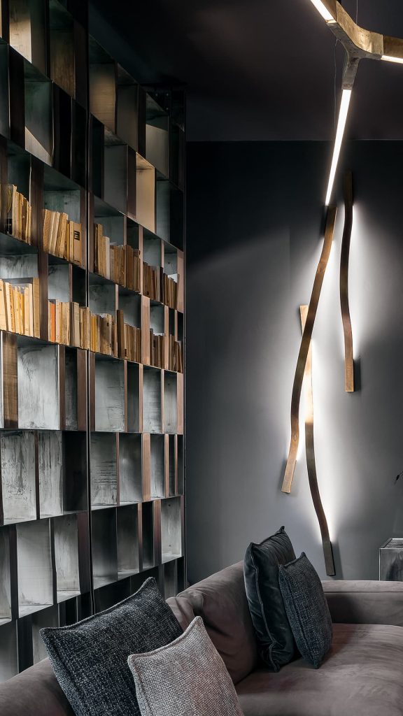 wall lamp made in the shape of a curved flame in burnished brass in a bronze tone in a room