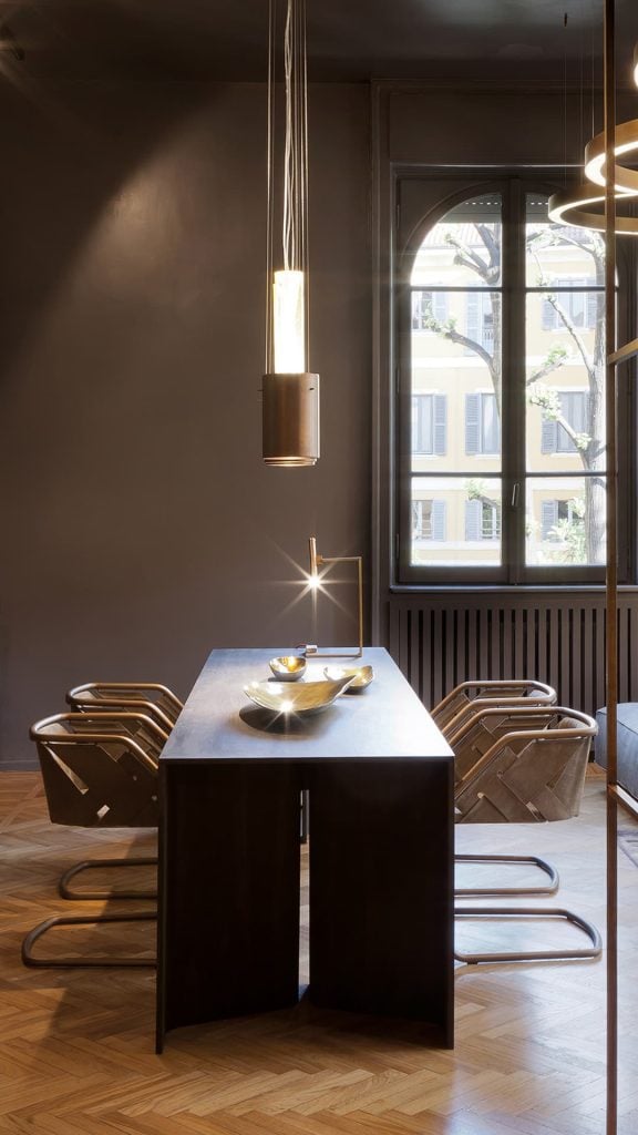 Time Table with two legs, structure in natural wood cover in burnished brass in a dining room.