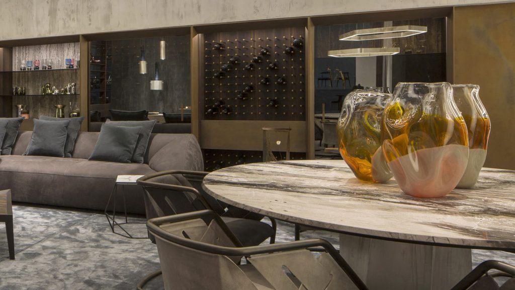 Zenith Table , white and black marble top, central leg in gold brass casing in a dining room.