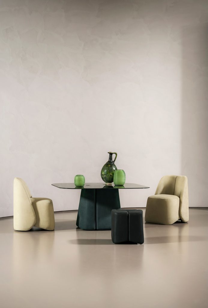 dining table made of velvet in a green tone and a black transparent glass top