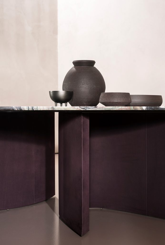 Drop-shaped table made of marble in a varied color tone in an office with a stone base in a brown tone