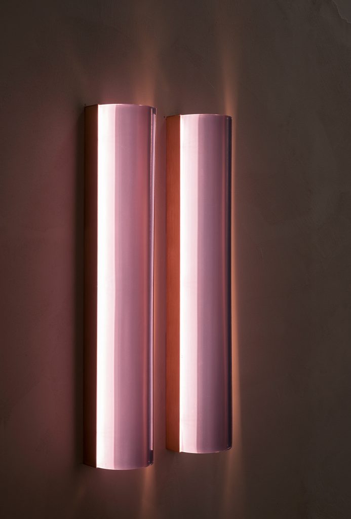 two-panel wall light made of glass and aluminum in a pink tone on a black background