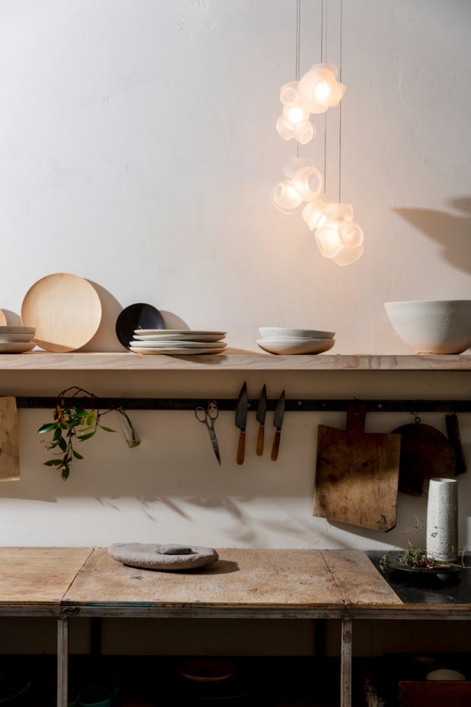 One Hundred Clear light hanging over a wooden table illuminated with plates on the table