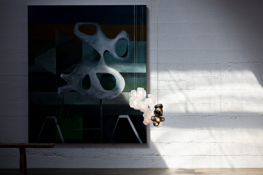 One Hundred Clear with Gray light hanging in front of an art work on a white wall