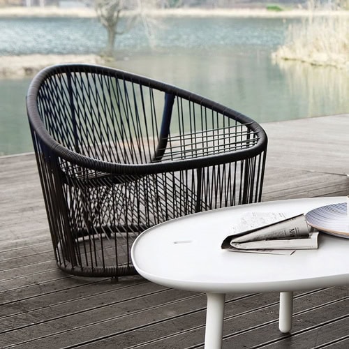Club armchair, seat, backrest and frame in brown metal in a garden.