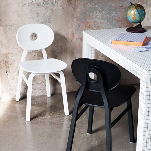 Two Elipse chairs, one in black and one in white with round back with four legs in a dining room.