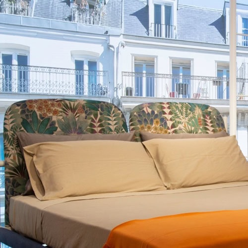 Florin bed. Headboard with green and pink floral pattern, base and four legs in wood upholstered in gray fabric in a bedroom.