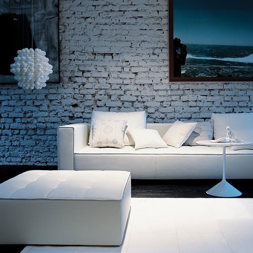Kilt sofa with metal legs and a cushioned seat and backrest in white fabric in a living room.