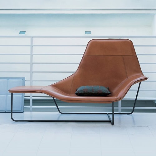 Lama lounge chair with wide, upholstered seat in brown leather and black metal frame in an office.