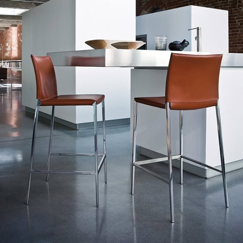Two Lio - Leo chairs with a minimalist design, featuring a metal frame and a brown upholstered seat and backrest in a kitchen bar.