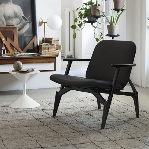 Black Louise chair with a classic, elegant design, featuring a cushioned seat and backrest, and a wooden frame in a living room.
