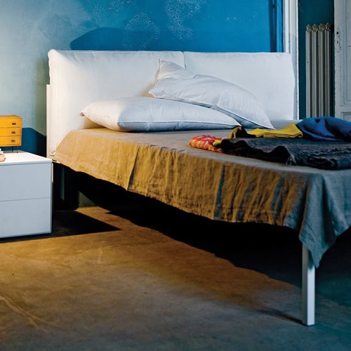 Nyx bed featuring a padded headboard and white frame and four legs in a bedroom.