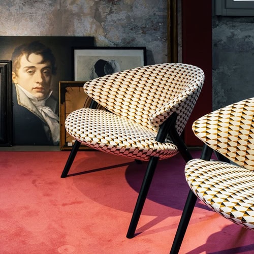 Two Oliva chairs featuring a black frame and a white and yellow upholstered seat and backrest with triangles pattern in a living room.