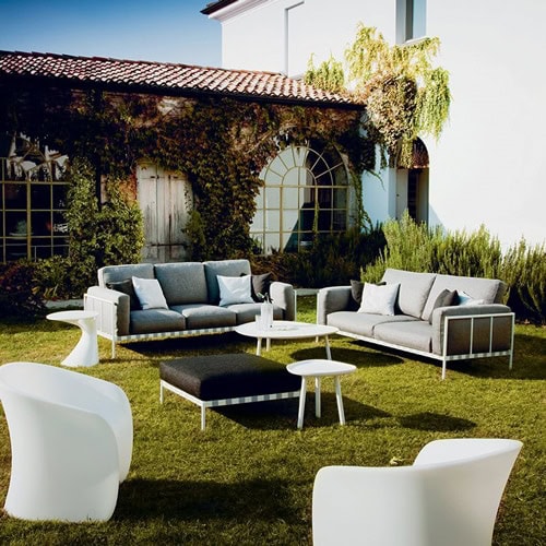 Two Parco benchs with gray cushion, supported by a white metal frame on a garden.