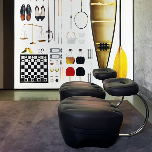 Two Primate chair upholstered in black leather with a steel leg in a living room.