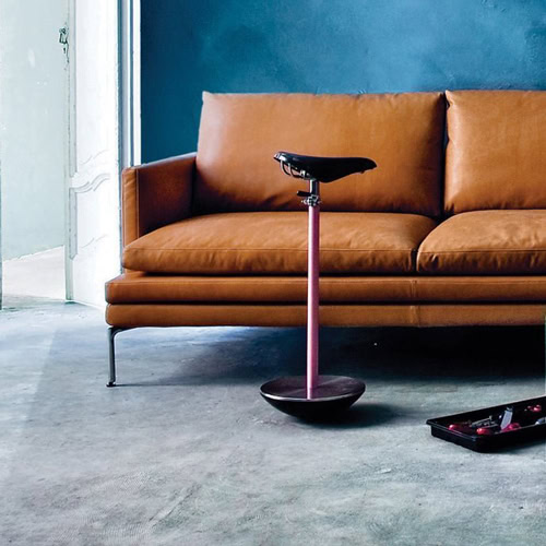 Sella stool with a unique design, featuring a black seat and a pink metal base in a living room.