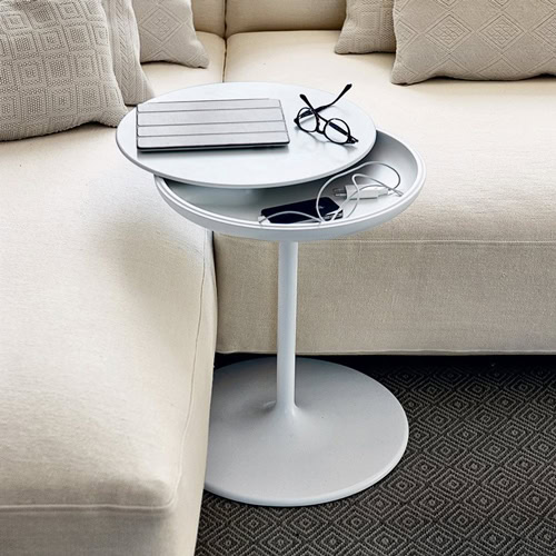 Toi side table with a round white top and central leg, in a living room.