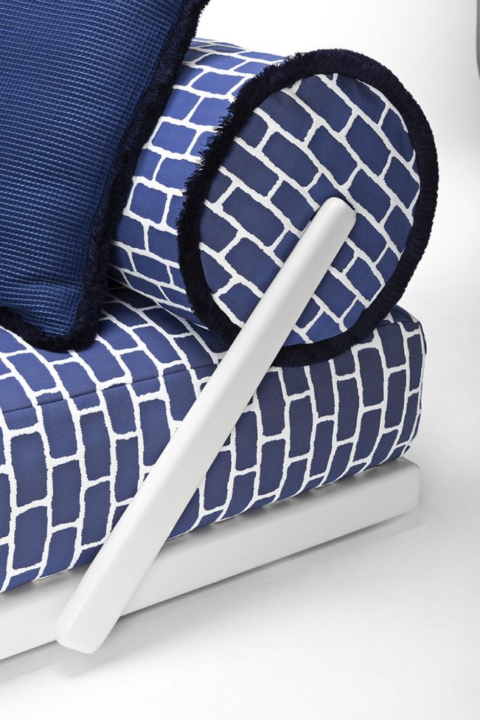 bed with blue and white cushions and white wood trim on a white background