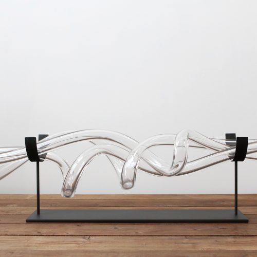 twisted tubes of cut and polished blown glass on a white background.
